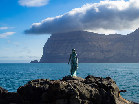 K&oacute;pakonan, the seal woman, statue over the rocks by the Kalsoyarfj&oslash;r&eth;ur fjord with Kynoy island in background