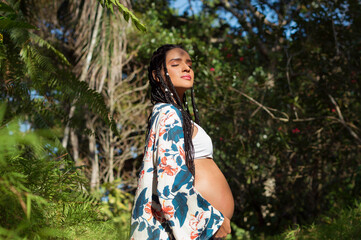 pregnant brunette woman with braids enjoying the sun and her vitamins. Healthy and happy pregnancy concept.