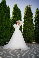 beautiful bride posing in a white delicate dress in the park.