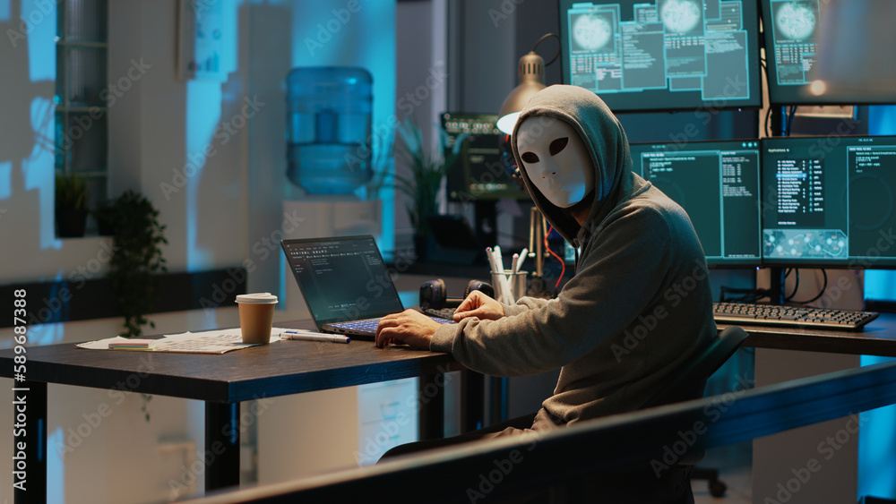 Poster cyber impostor with anonymous mask breaking security system, installing virus to create computer mal
