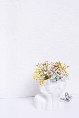 Mental health concept. Creative vase head-shape with colorful flowers and butterfly on white background