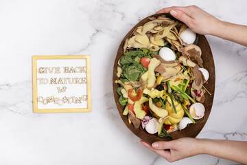 Give back to nature is composting text with organic garbage for compost on a marble background....