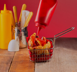 Fresh chips in a basket with tomato sauce being squirted over them.