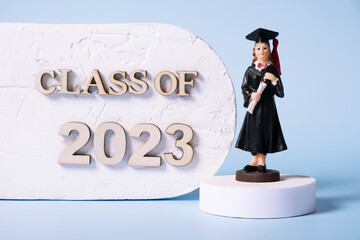 Class of 2023 concept. Wooden number 2023 with graduate statuette on color background