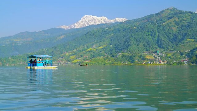 Tourists on a boat on Phewa lake taking in the beautiful Himalayan landscape and snowy Annapurna mountain peaks, Lakeside Pokhara, Nepal