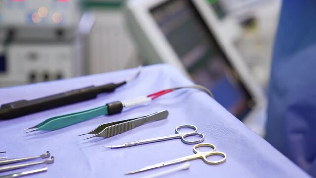 Surgical scissors, forceps and electric medical devices on the table in surgery room. Close up. Blurred backdrop.