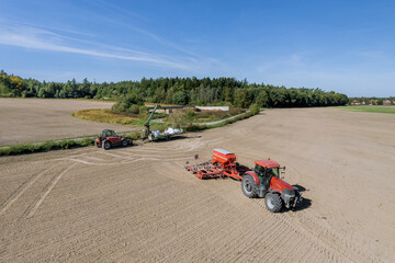 Grain loader and a tractor with a seeder in the field. Cereal sowing according to modern technology. Transportation of goods, movement of special equipment.