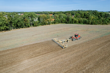 Red big tractor milling the ground. Tractor milling of the land in the field, agricultural spring work with the help of modern equipment. Top view of tractor operation.