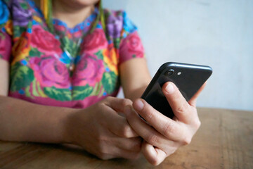 Guatemalan woman in traditional huipil dress working with laptop and smartphone