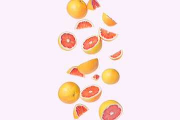 Sliced grapefruit flying isolated on a pink background. Summer aesthetic fruit concept.