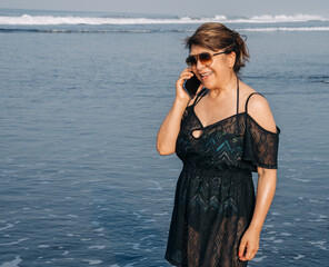 Woman enjoying a morning phone call at the beach. Concept of cell phone service everywhere.