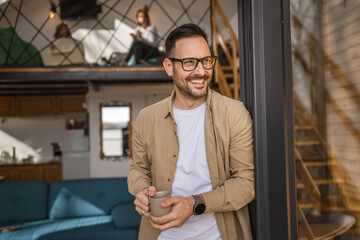 One adult man stand in at door of tiny house happy smile hold cup