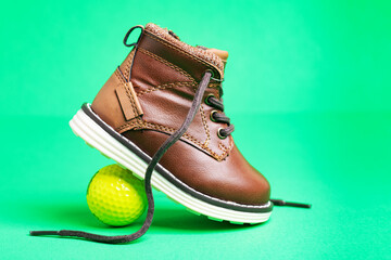 Fototapeta na wymiar children's leather shoes with laces and a ball on a green background. Close-up.