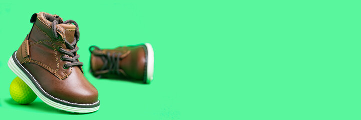 children's leather shoes with laces and a ball on a green background. Space for text.