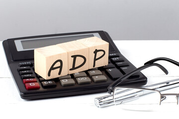 ADP concept on wooden cubes on calculator on white background