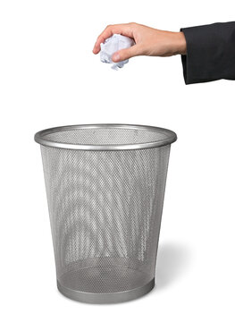 Hand throwing out paper into trash basket isolated on white