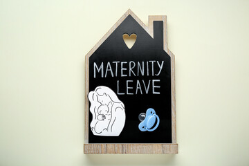 Maternity leave concept. Wooden house figure, baby pacifier and paper cutout on white background, top view