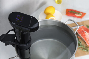 Sous vide cooker in pot on white table, closeup. Thermal immersion circulator
