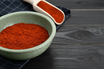Bowl and scoop of aromatic powder on black wooden table. Space for text