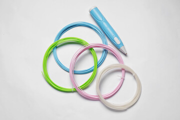 Fototapeta premium Stylish 3D pen and colorful plastic filaments on white background, flat lay