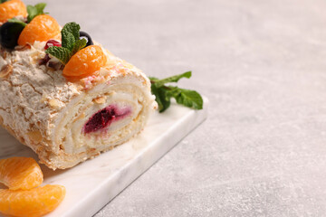 Tasty meringue roll with jam, tangerine slices and mint leaves on grey table, closeup. Space for text