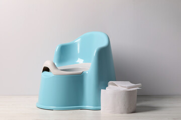 Baby potty and toilet paper near light wall