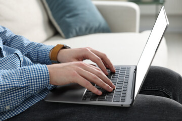 Man working with laptop on sofa indoors, closeup