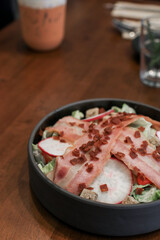 Salad with bacon, croutons and lettuce close-up on a plate on a table. Classic American salad, food. Healthy Keto diet. Copy space.