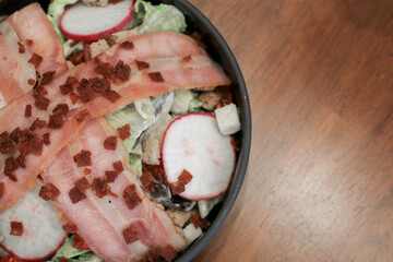 Salad with bacon, croutons and lettuce close-up on a plate on a table. Classic American salad, food. Healthy Keto diet. Copy space.
