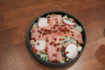 Salad with bacon, croutons and lettuce close-up on a plate on a table. Classic American salad, food. Healthy Keto diet. Copy space.