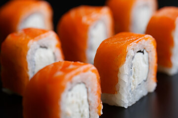 Philadelphia roll with salmon, cheese and rice, on a black background. Macro. Selective focus.