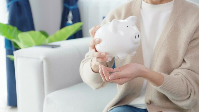 Young asian woman attempting to take money coin from piggy bank. Save money and investment concept