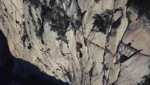 Granite cliff wall aerial tilt of sky plank path high on Mount Huashan