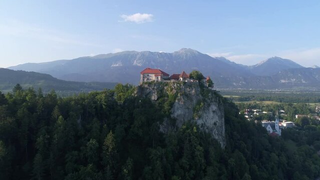 Establishing shot of Bled Castle perched ontop of a mountain with tourists exploring