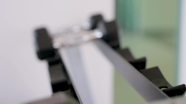 Black dumbbell row set. Hand pickup metal dumbbells on rack in sport fitness gym, Weight training equipment
