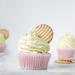 Pink cupcakes with tall american buttercream swirl and cookie garnish, cupcakes in pink liners with a tall vanilla buttercream and a cookie, birthday cupcakes on a white background