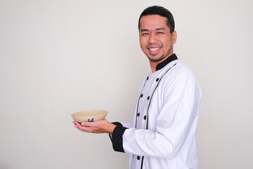 Side view of a Chef smiling at the camera while holding empty dinner bowl