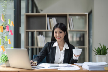 Fototapeta na wymiar Happy young business Asian girl working at a office with coffee and laptop