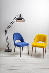 minimalistic interior, blue and yellow armchair, small coffee table and a huge floor lamp against the background of a white wall and a white wooden floor