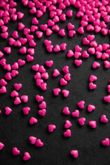 Pink heart sugar sprinkles scattered on dark