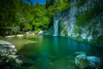 Fototapeta na wymiar Beautiful landscape. Small lake and forest waterfall. Clear spring water. Nature background.