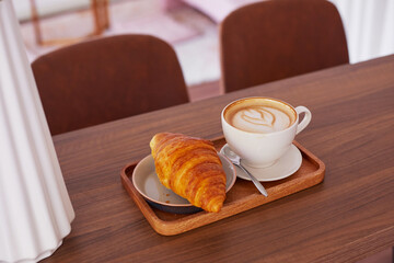 Сup of coffee and a croissant in a cafe.