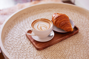 Сup of coffee and a croissant in a cafe.