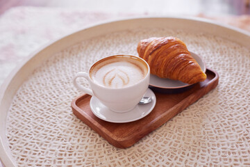 Сup of coffee and a croissant in a cafe.