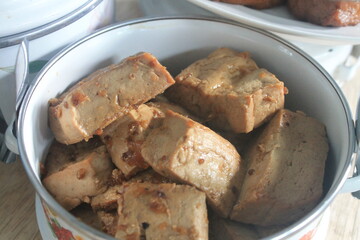 Indonesian food called tahu bacem made from tofu in a white plate on a wooden table