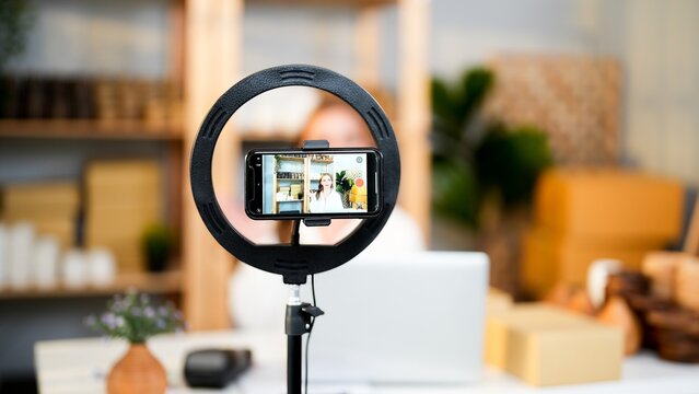 Record live video and sharing product promotion on social media with ring light and smartphone horizontal rotate and Caucasian seller woman in screen