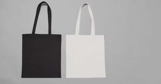 Close up of white and black bags on grey background, with copy space, slow motion