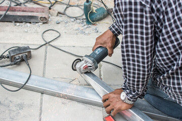 worker cuts a metal pipe with some electric device or appliance