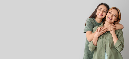 Portrait of happy young woman hugging her mother on grey background with space for text
