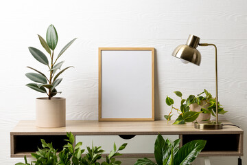 Wood empty frame with copy space, lamp and plants in pots on table against white wall